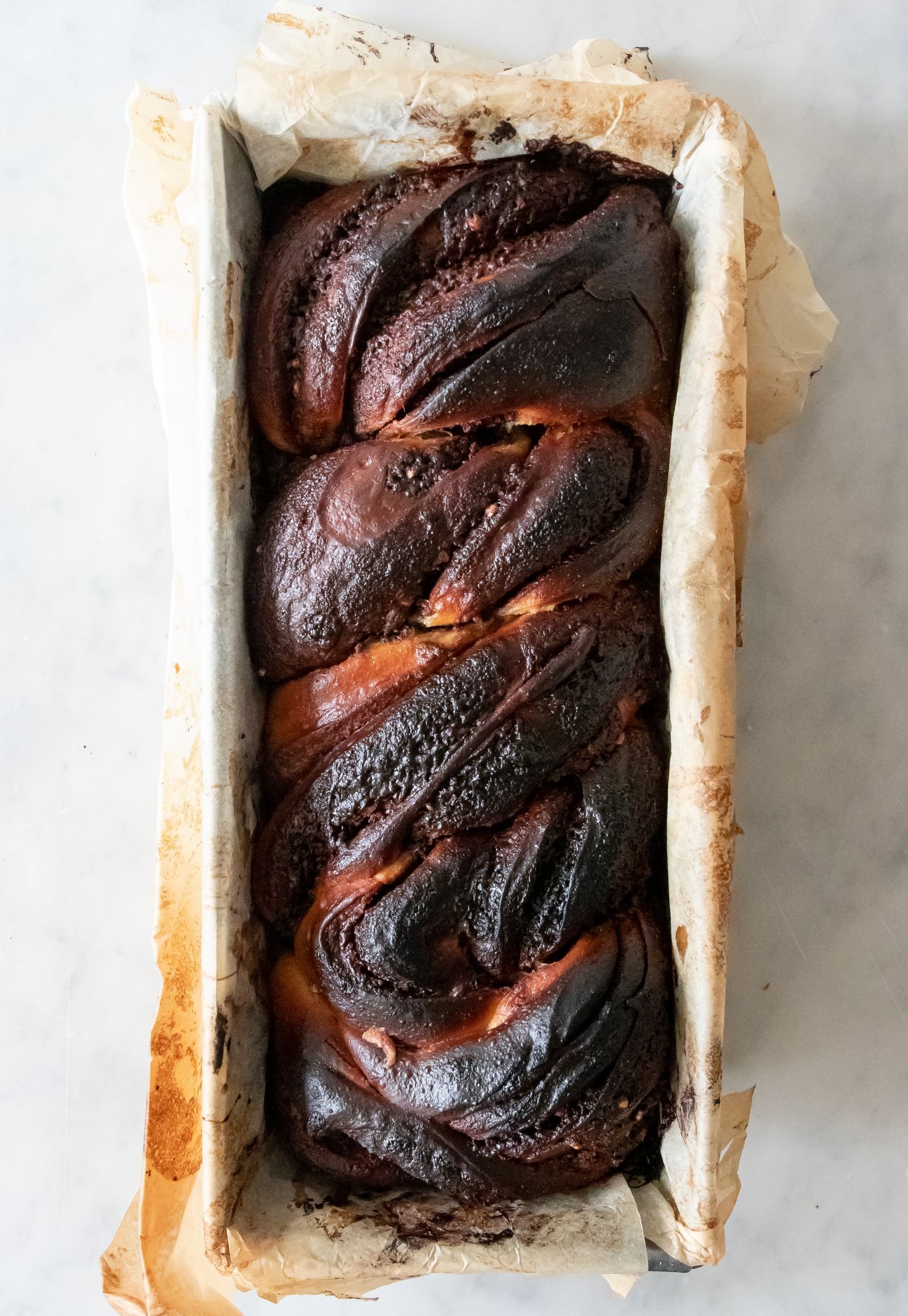 Chocolate swirl babka in a parchment-lined loaf tin seen from above